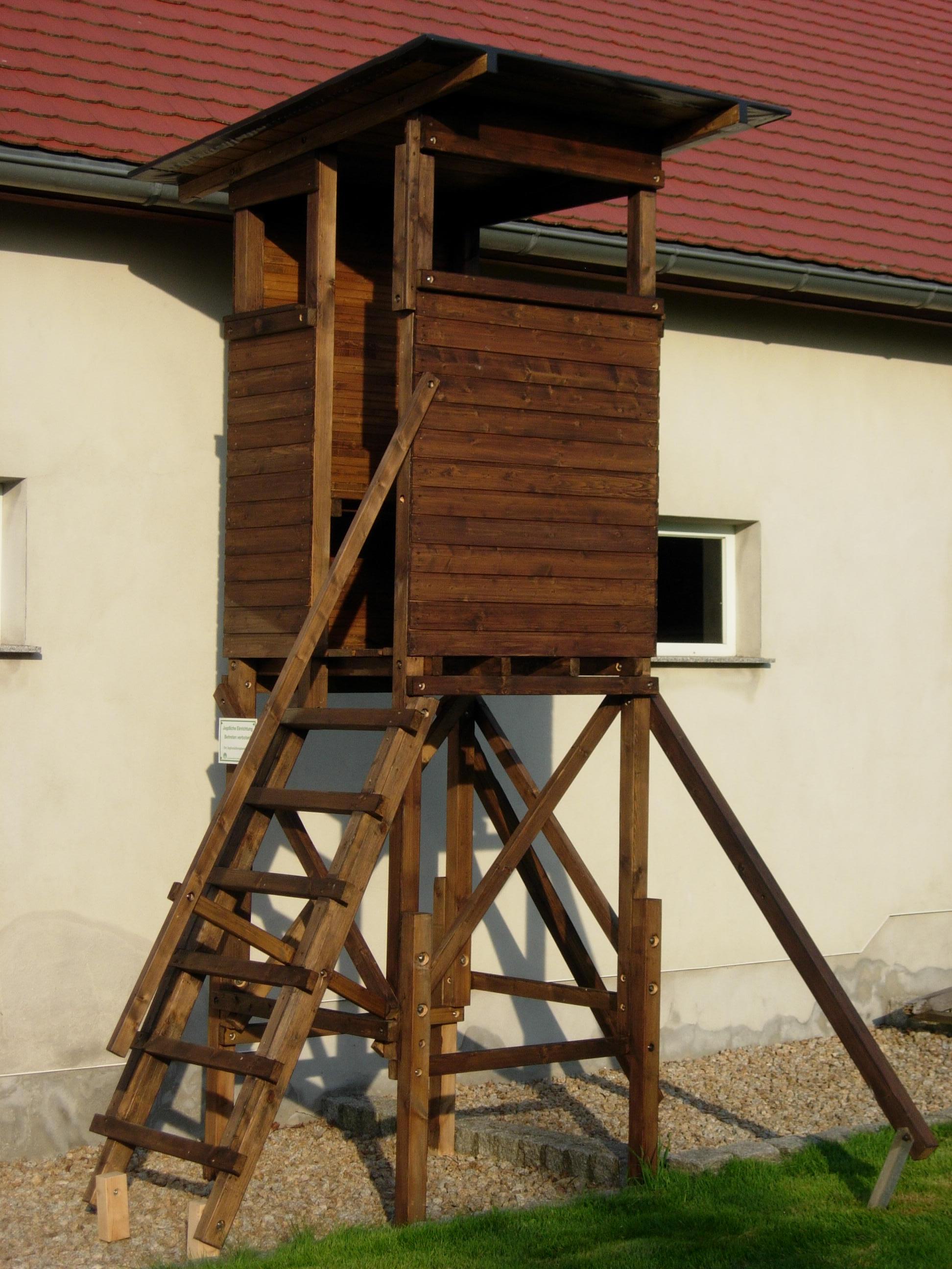 Offene Kanzel mit integriertem Dach, R&uuml;ckseite vollverkleidet, fest installiertes Sitzbrett, Ablagebretter, im Frontbreich mit ausgespartem Gewehrhalter, 6-stufige Leiter, Handlauf, Abstrebungen mit Erdanker (optional).
Gesamth&ouml;he ca. 350 cm, Grundfl&auml;che 100 x 100 cm.